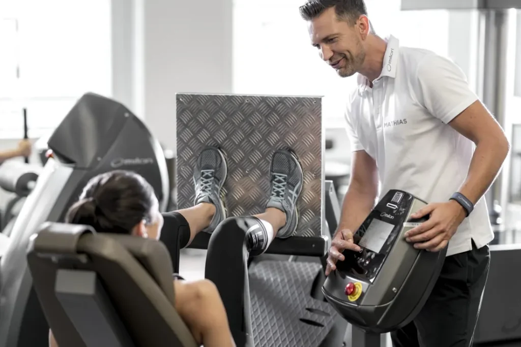 Trainer erklärt eine Übung an der milon-Beinpresse